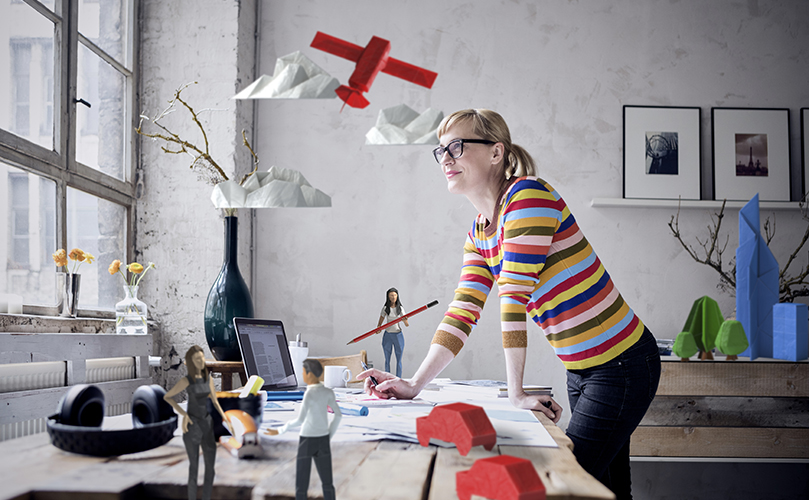 A person standing at a table with a laptop and a red object