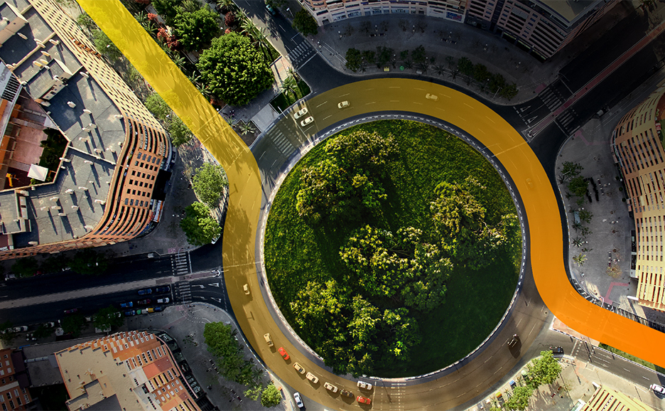A roundabout with trees in a center, surrounded by buildings