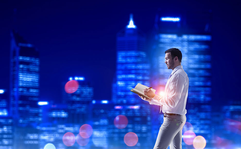 Man writing in a notebook against a city night view.