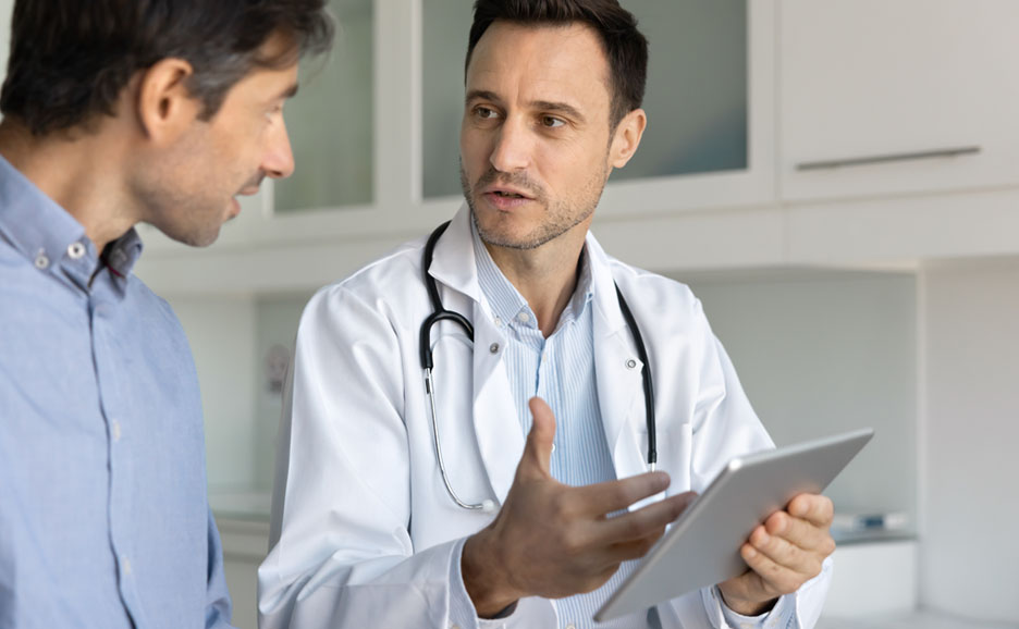 Male doctor explaining tablet information to a patient