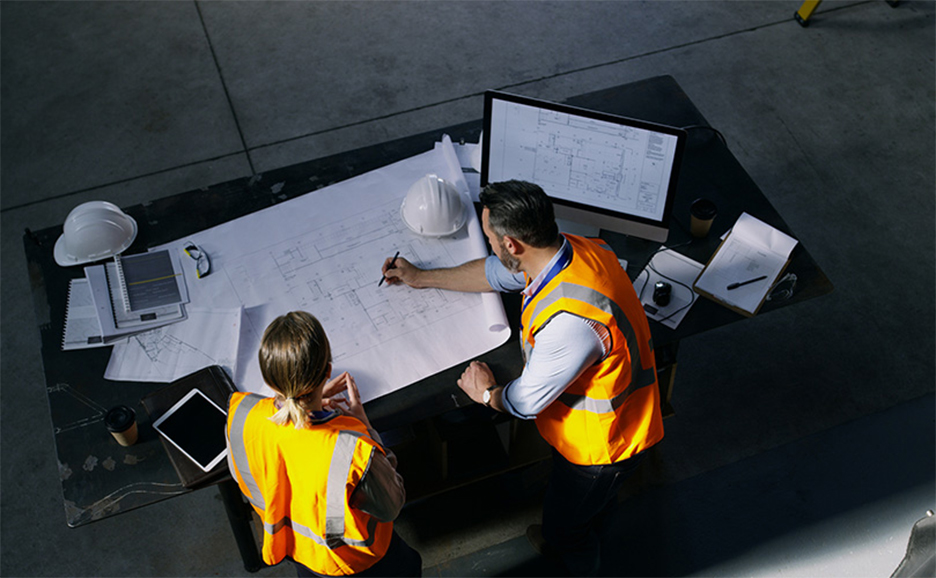 Man and woman checking blueprints on a large desk