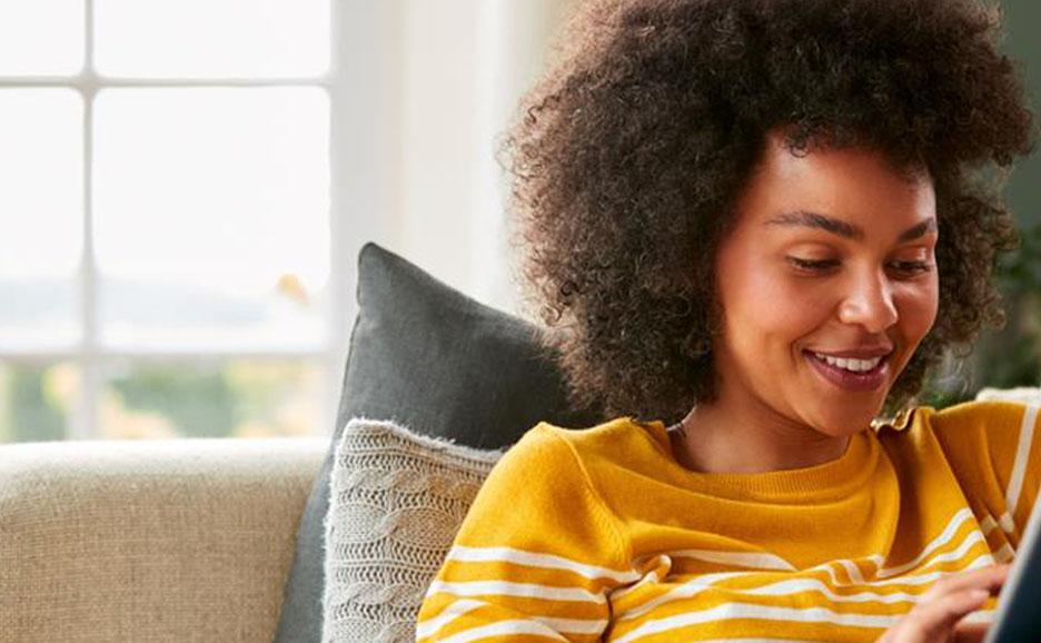 A woman in a yellow top looking at a device at home.