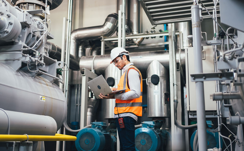 Engineer using laptop controlling program to automate large machinery