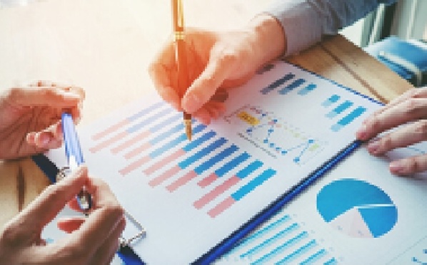 Someone taking notes on documents with various graphs