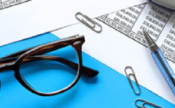 An image of scattered paper, clips, glasses, and pens