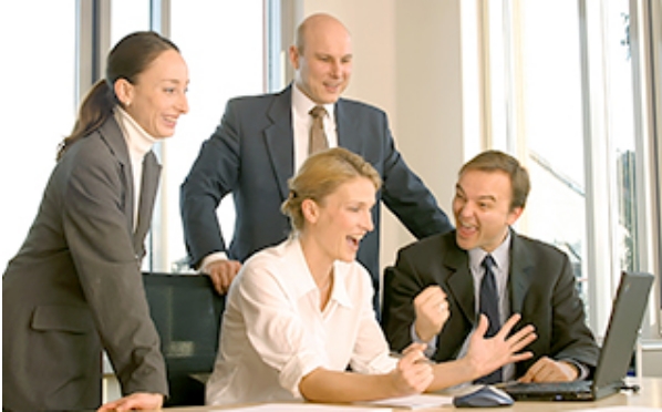 Four businesspeople chatting in front of computers