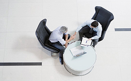 An overhead view of two businessmen sitting around a coffee table, engaged in discussion
