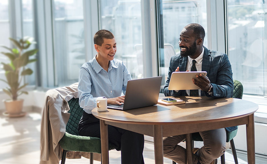 Smiling colleagues collaborating on laptop in office