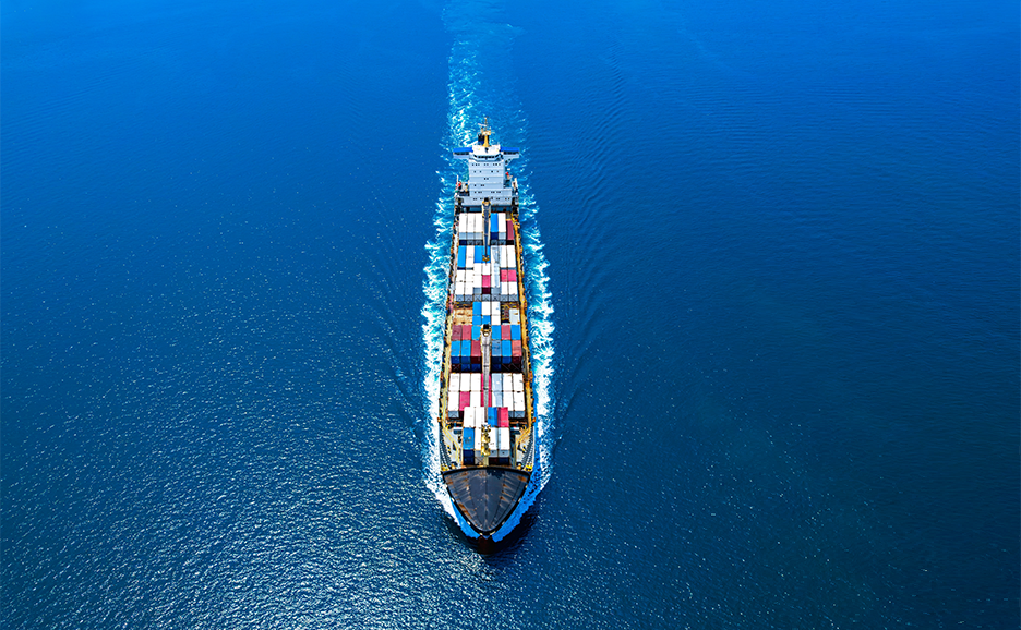 An aerial view of a container ship loaded with cargo sailing on the blue sea.